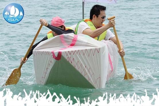 the cardboard boat building race begins with a succesfully built craft at sea being paddled by a crew of two